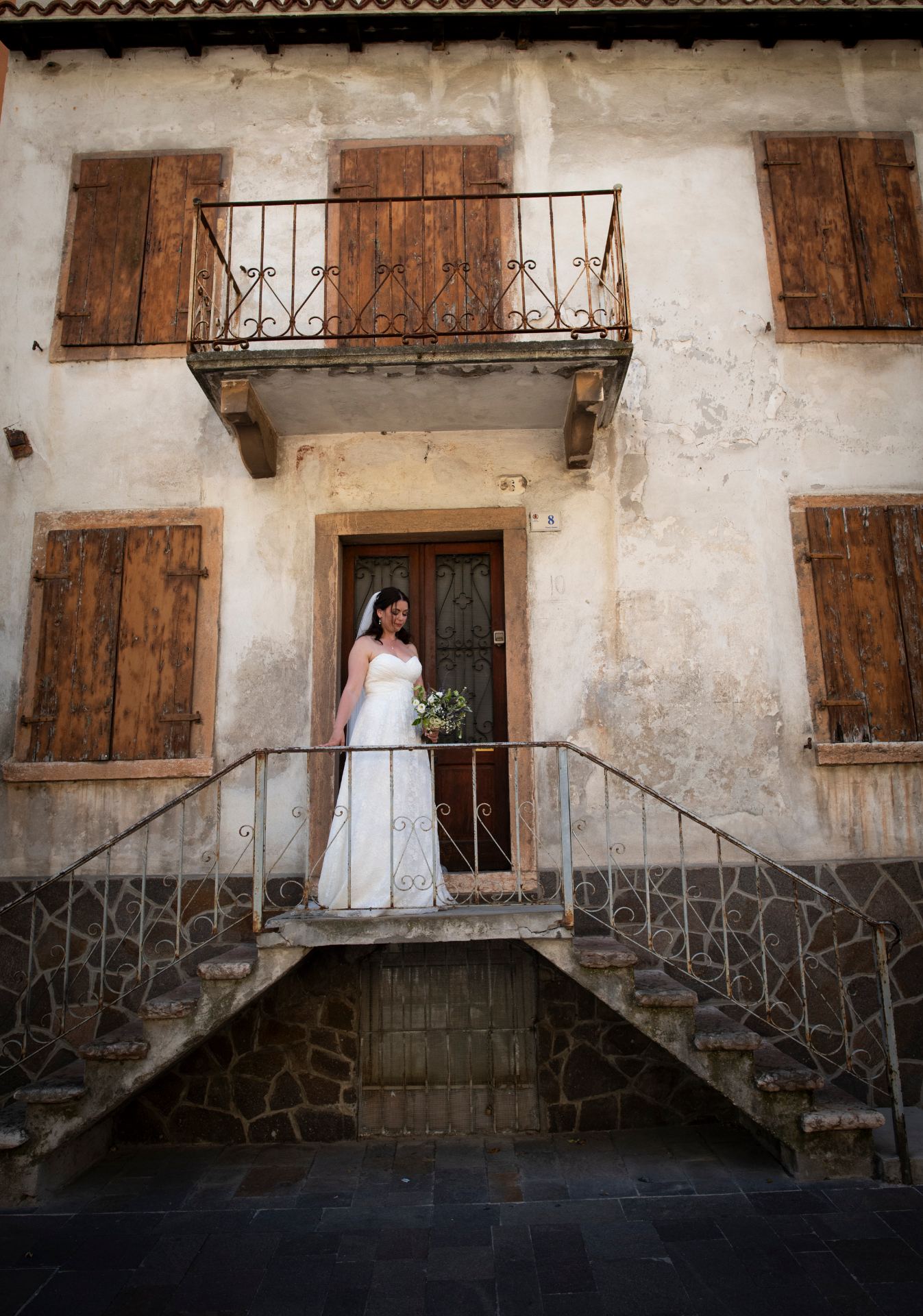 Bride standing on a rustic Italian staircase outside an old stone house