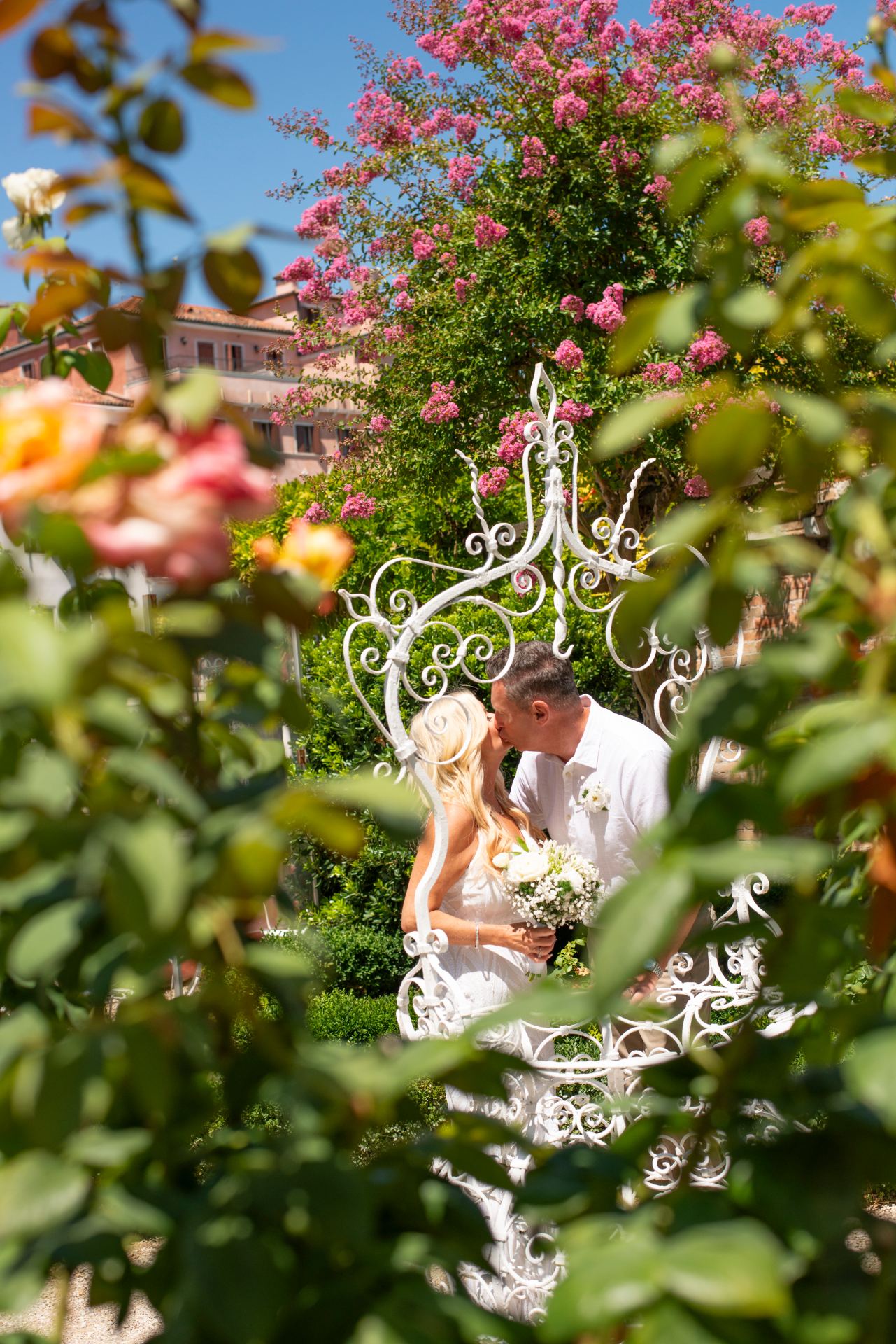 Couple kissing in a beautiful Italian garden surrounded by pink flowers