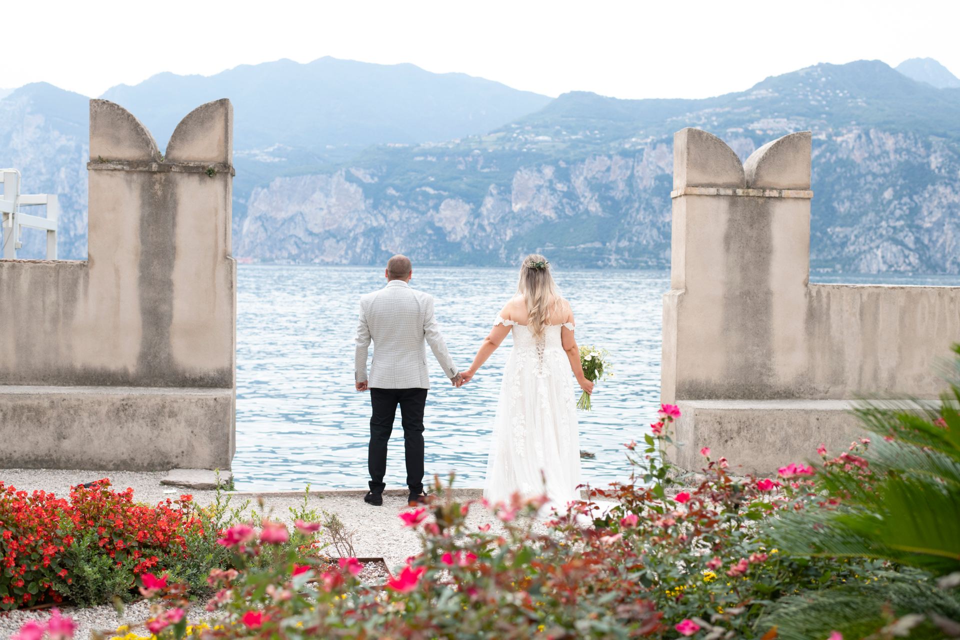 Couple standing by the lake looking out at the mountains of Lake Garda
